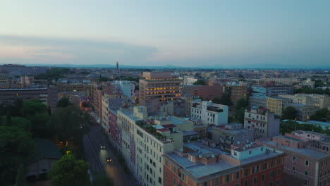 Diapositiva-Y-Toma-Panorámica-De-La-Casa-Soho-Iluminada.-Volar-Por-Encima-De-Los-Edificios-En-El-Distrito-Urbano-Al-Atardecer.-Roma,-Italia