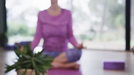 multiracial women practicing patience mudra while meditating in yoga class