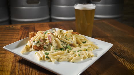 creamy penne pasta dish on white square dish paired with light beer, slider 4k