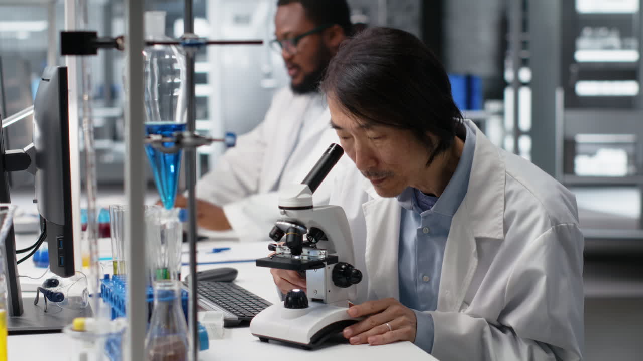 Vertical video Senior microbiologist in lab using scientific microscope to detect disease