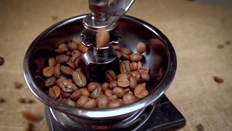 los granos de café caen en el viejo molinillo. cámara lenta con seguimiento de rotación.