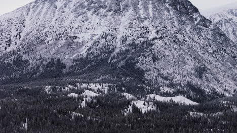 cinematic aerial view of the imposing snow-covered mountains and dense forests surrounding the takhini river and kusawa lake in yukon, canada. a breathtaking winter wilderness scene.