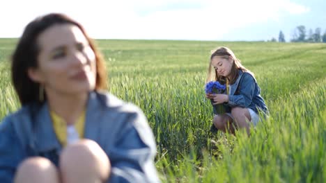 blurred portrait of mother daughter playing with plucked flowers in tall green grass blurred portrait of mother daughter playing with plucked flowers in tall green grass in the middle of the field family vacation in nature