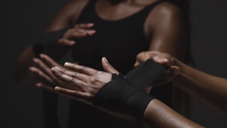 studio shot of women putting on boxing wraps on hands before exercising together