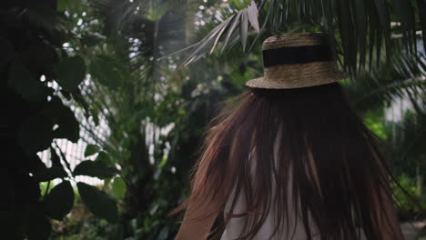 mujer en un vestido blanco caminando a través de un invernadero tropical