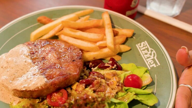 Bistec a la parrilla con papas fritas y ensalada fresca en un plato