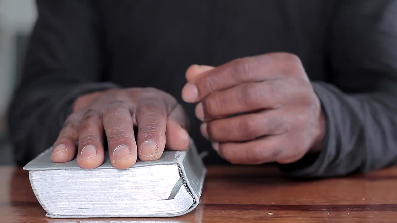 hombre negro orando a dios con la biblia en las manos hombre caribeño orando con el fondo con la gente stock video stock footage