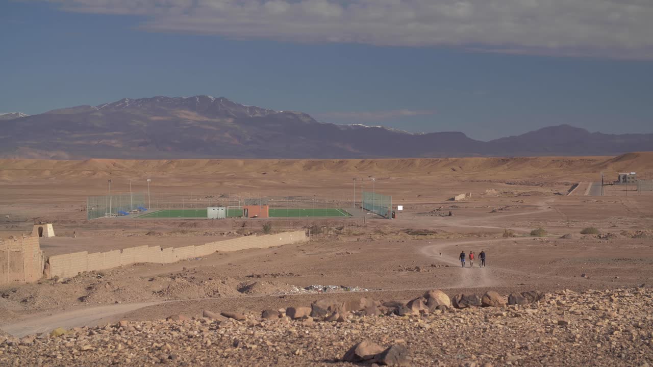 Un campo da calcio in mezzo al deserto a Ouarzazate con vista sulle montagne innevate