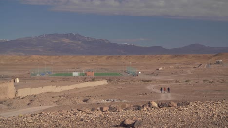 un campo de fútbol en medio del desierto en ouarzazate con vistas a las montañas nevadas