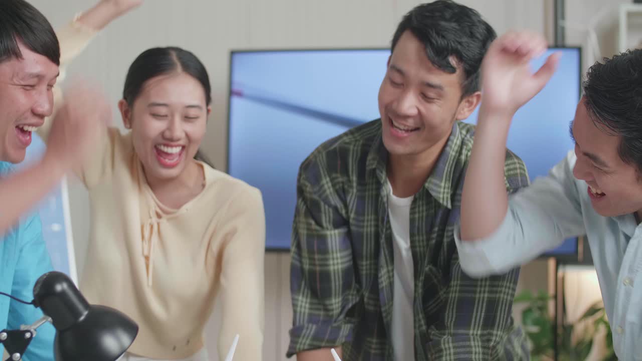 아시아 엔지니어 그룹이 사무실에서 풍력 터빈을 작업하는 동안 손을 합치고 있습니다.