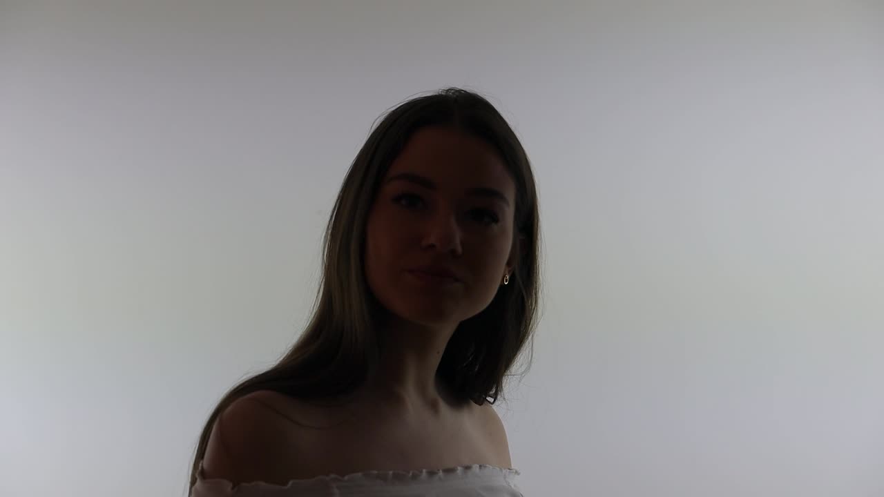 매력적인 여성 모델의 실루 ⁇ 이 머리카락을 고치고 카메라를 바라보고 있습니다.