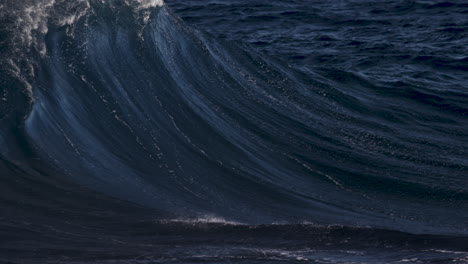 wave breaking in slow motion on a sunny day as spray blows back up the wave face thanks to a strong offshore wind