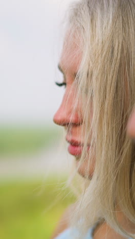pretty blonde lady with man stands together at romantic date on blurred background on spring day extreme close side view slow motion