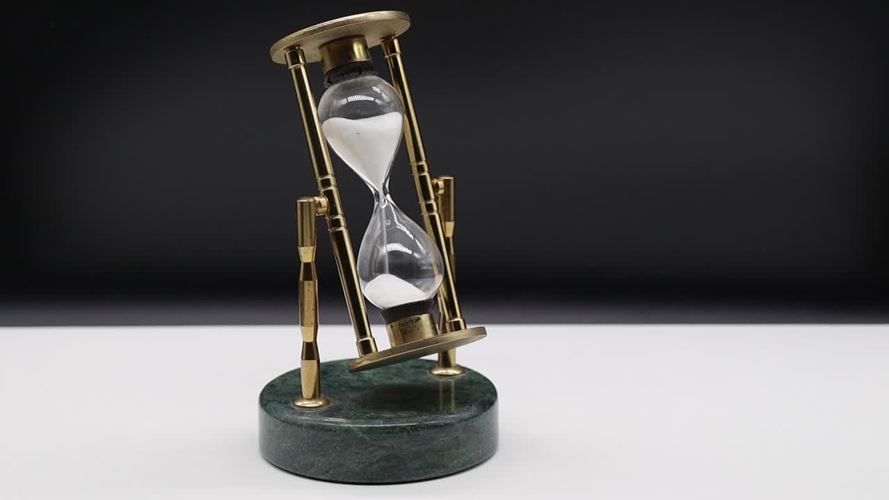 Hourglass on white table isolated on black background