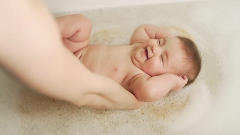 Mutterhände-Stehlen-Babymädchen-Auf-Einem-Schwamm-Im-Badezimmer