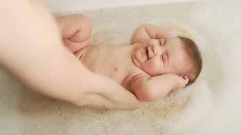 mother's hands steal baby girl on a sponge in the bathroom