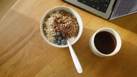 espacio de trabajo de madera soleado con un tazón de desayuno nutritivo y café