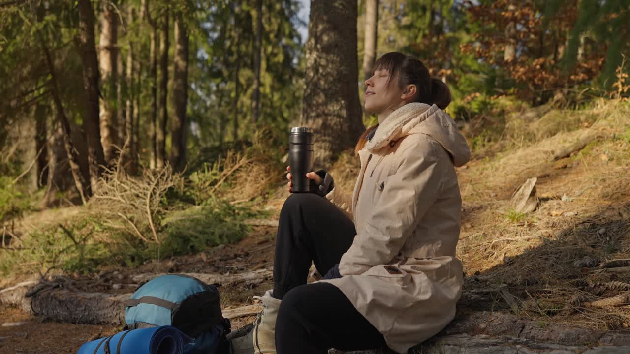 Donna che si gusta una bevanda nella foresta durante un'escursione