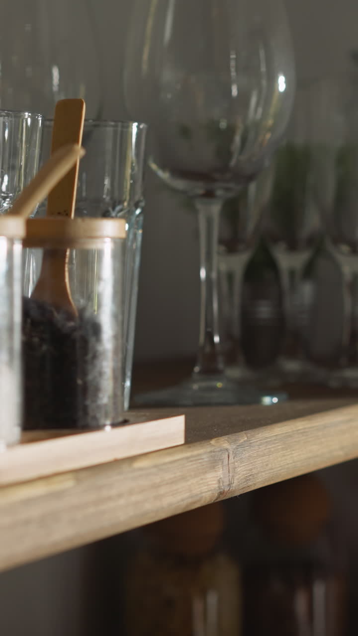 una mujer toma café del armario en el primer plano de la cocina. una mujer alcanza un frasco de vidrio con granos de café en un estante de madera en casa. hacer bebida caliente