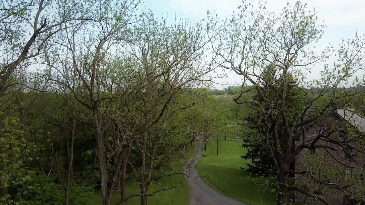 오른쪽에 돌로 된 농가와 분리된 진입로가 있는 펜실베니아 서부의 나무 꼭대기에서 지상으로 공중으로 내려가는 것