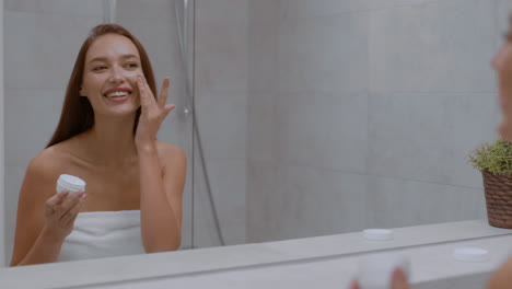 женщина наносит крем для лица