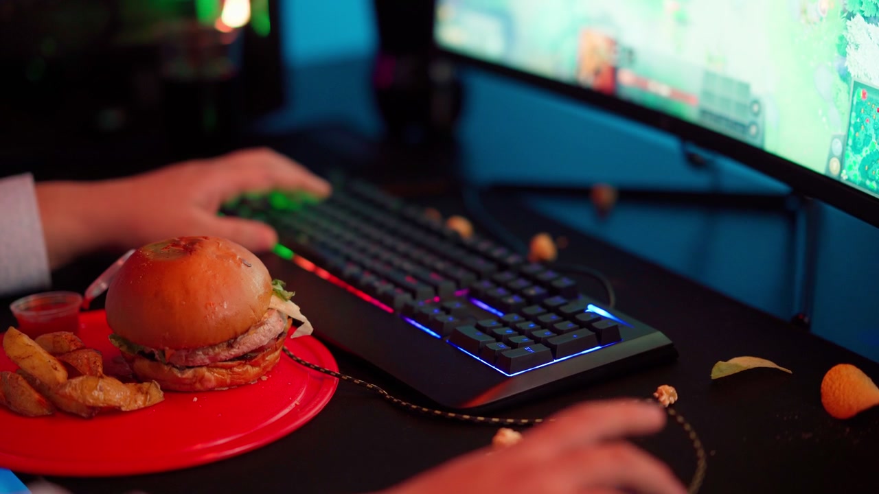 Gamer's Hands Playing with Fast Food and RGB Keyboard
