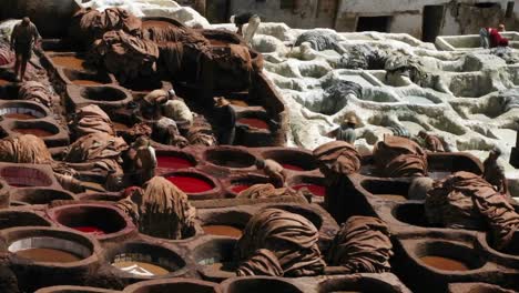 a time lapse of people dying clothes in large clay vats