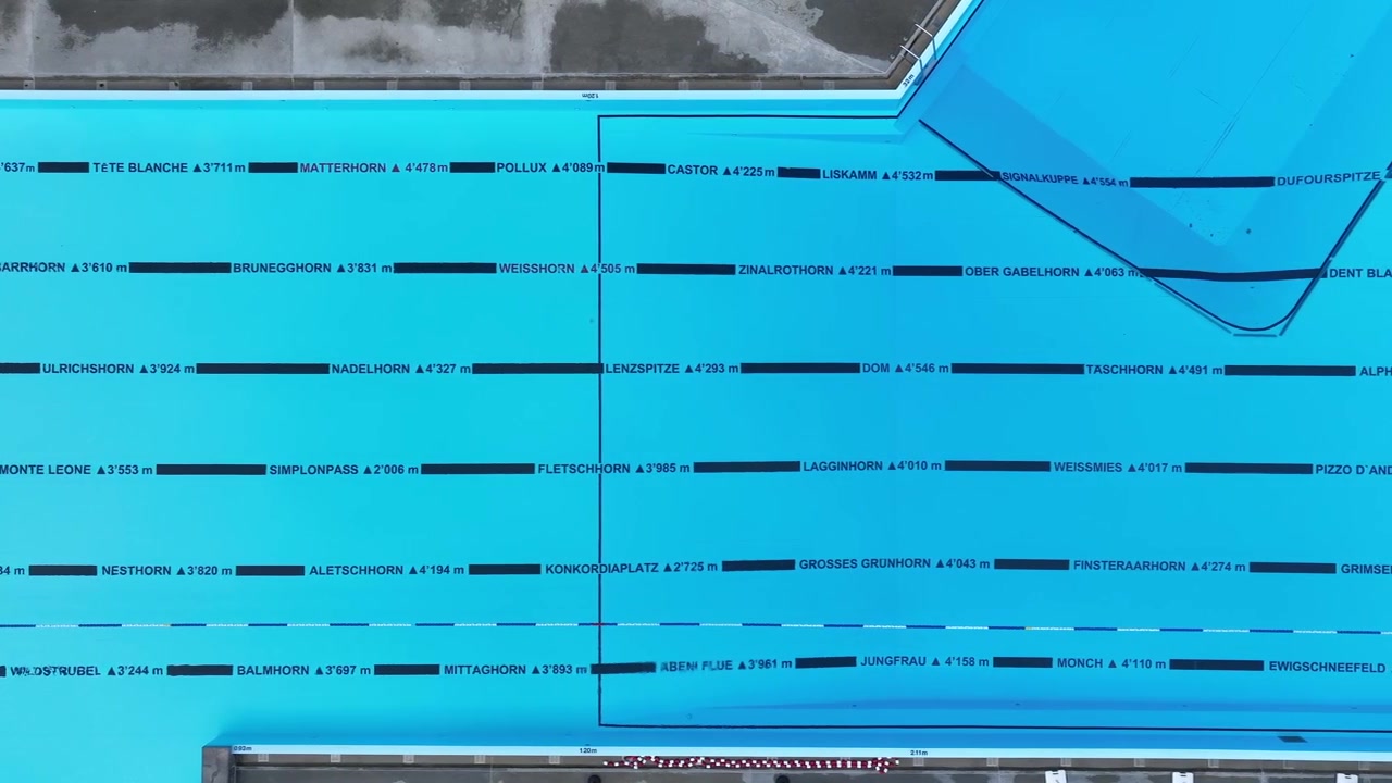 Panorâmica aérea em close-up sobre uma piscina de raias suíça com raias claras e nomes de montanhas com elevação