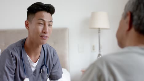 diverse male doctor and senior male patient discussing at home, slow motion