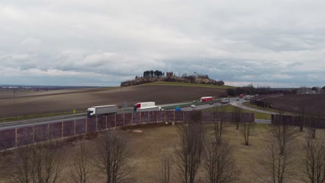 Fliegen-In-Richtung-Einer-Autobahn-Mit-Verkehr-Und-Einem-Hügel-Mit-Alten-Ruinen-Dahinter-Und-Einem-Bewölkten-Himmel-Darüber