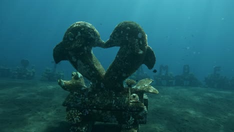 kissing-dolphin-statue-underwater,-deep-sea-Tulamben-ocean-monument,-Bali-scuba-diving