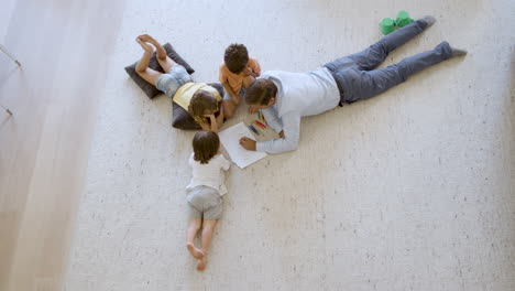 top view of sibling children and dad sitting and lying on floor