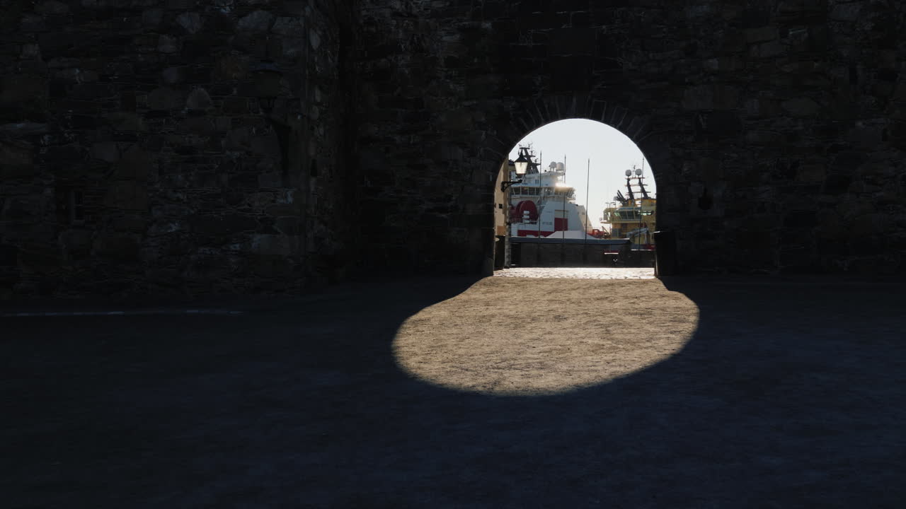 고대 요새 벽의 아치를 통해 바다 항구의 전망 그림자가 아름다운 ov를 만듭니다.