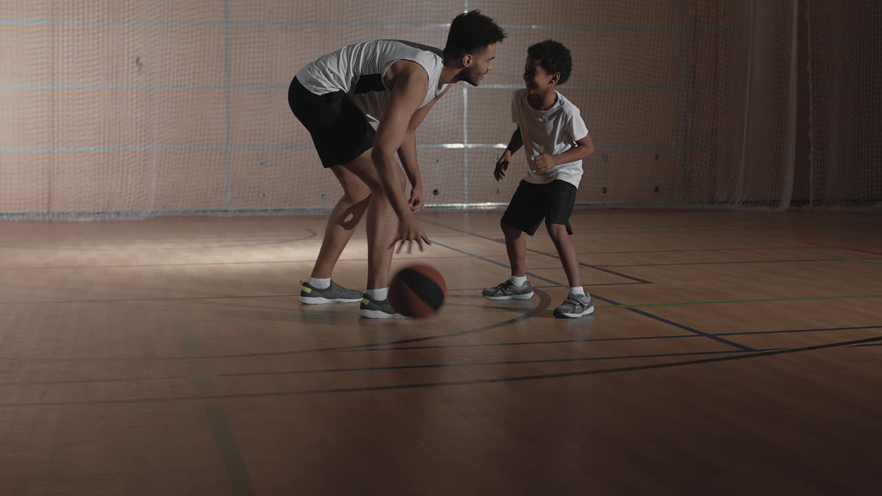 Slowmo of Father and Son Playing Basketball on Indoor Court