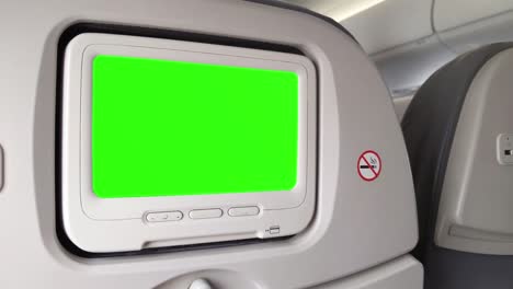 white lcd screen in an airplane seat turning on chroma key green screen. zoom in. close up. 4k.