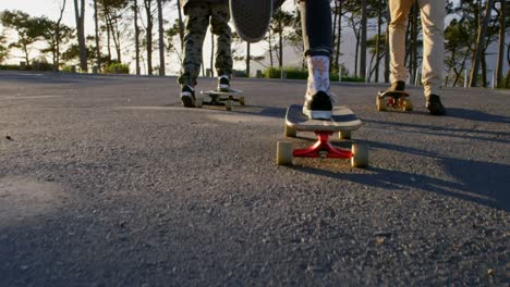 Rear-view-of-young-skateboarders-riding-on-skateboard-on-country-road-4k