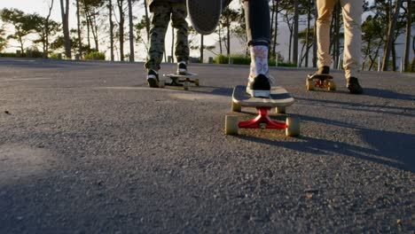 vista trasera de jóvenes patinadores montando en patineta en una carretera de campo 4k