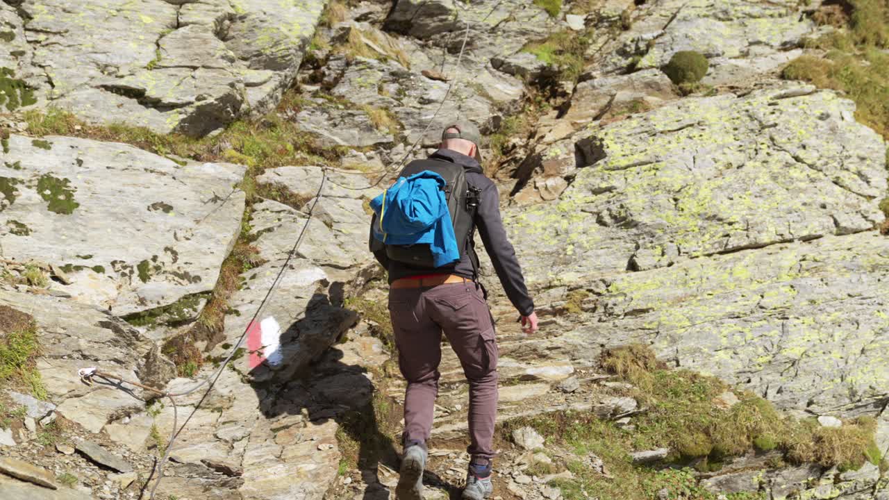un excursionista masculino sube por un sendero en la ladera de una montaña, italia