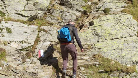 male hiker climbs along gr path on mountainside, italy