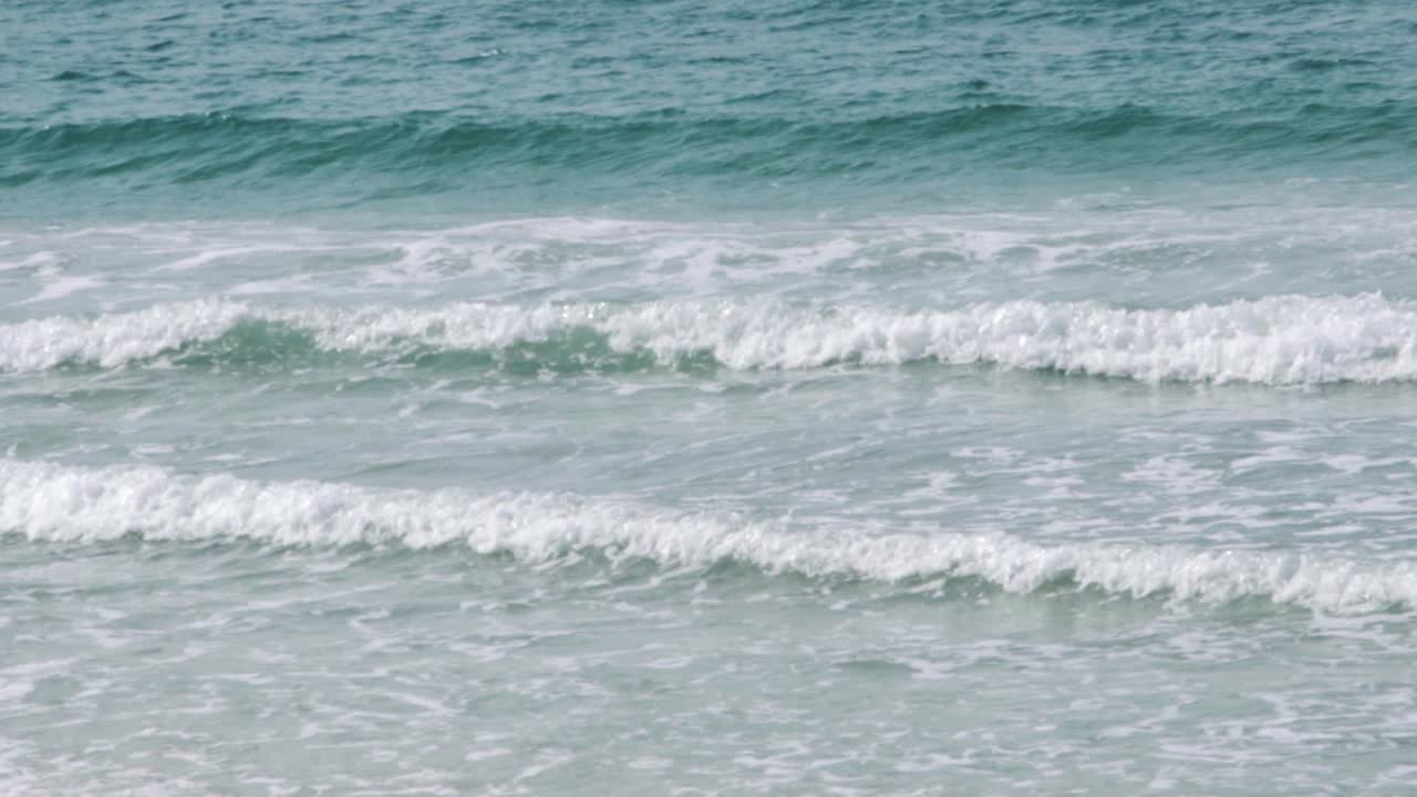 Ondas pequenas quebrando na praia em câmera lenta