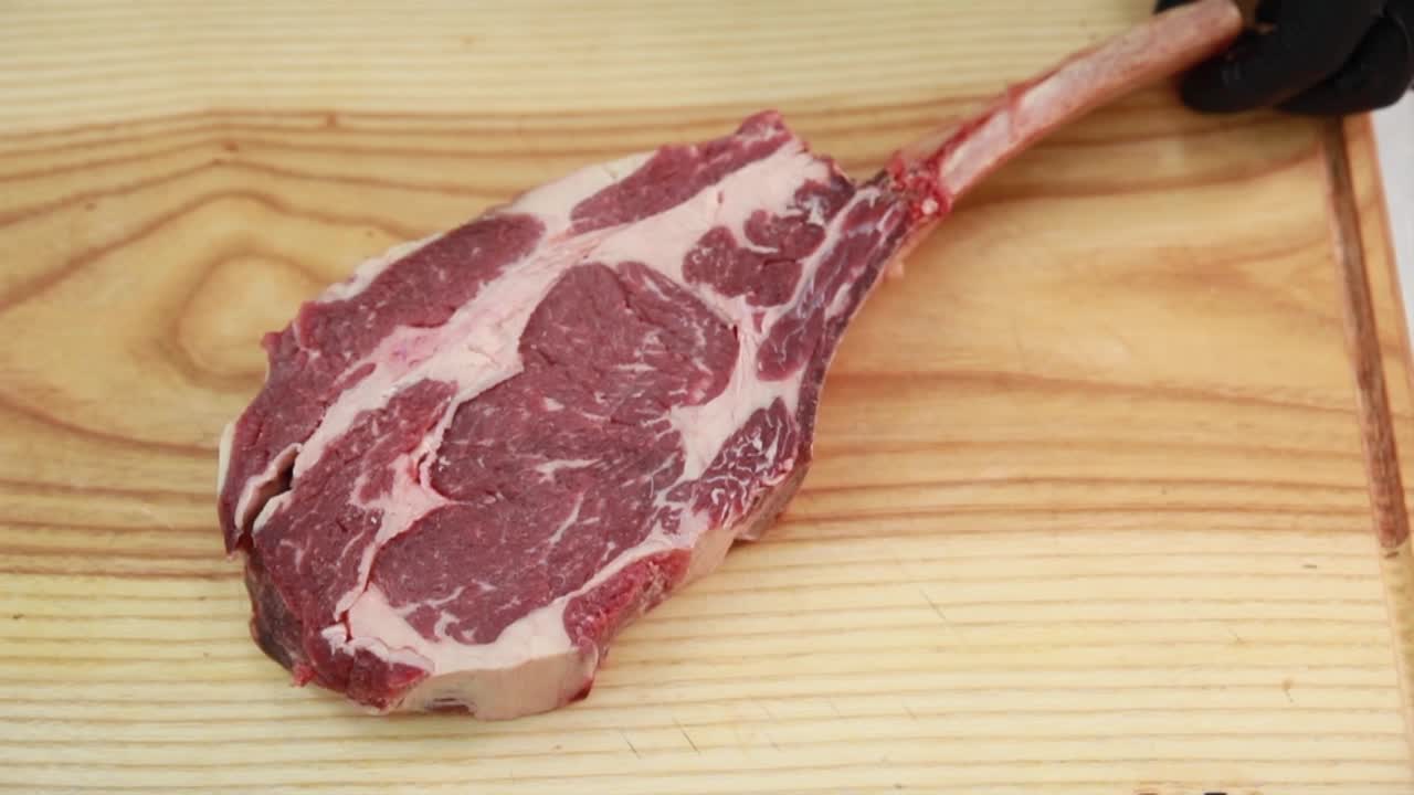 Filete de costilla cruda sobre tabla de cortar de madera