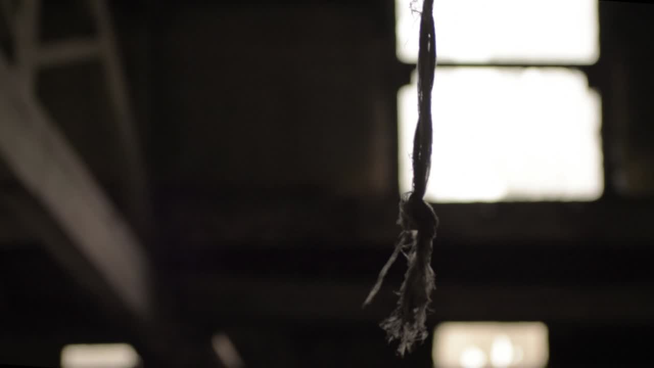 cuerda que se balancea desde el techo contra la ventana del edificio antiguo