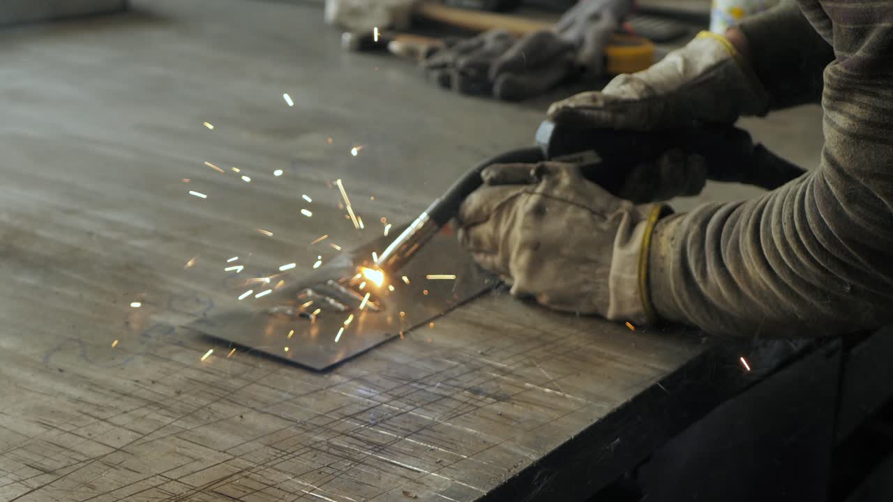 Welder on the table welds a set of metal parts