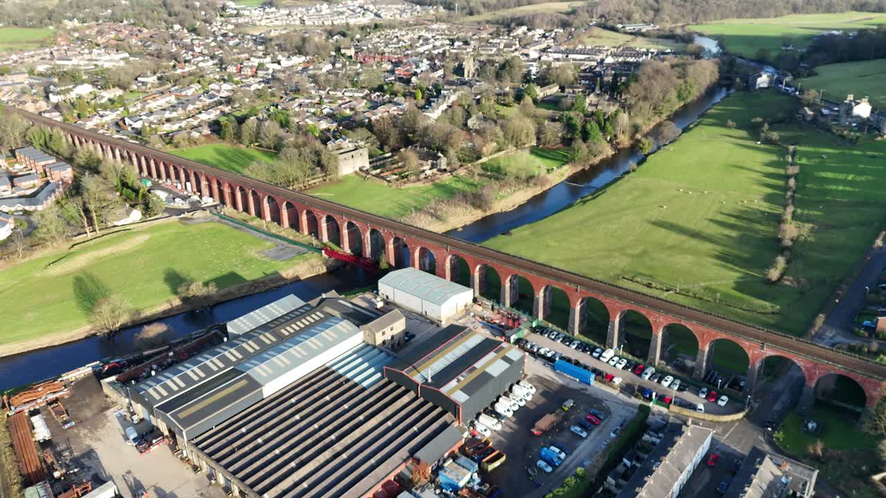 Captivating aerial footage of Conisbrough Viaduct in South Yorkshire, England. Sunlit town, lush fields, and winding river create a tranquil, scenic landscape with no people visible