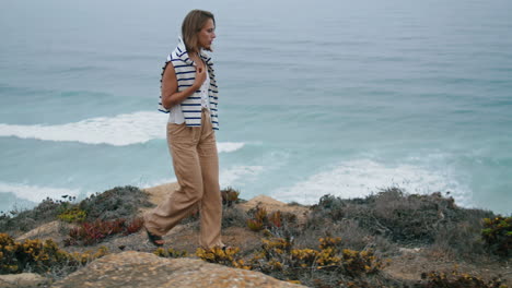 tourist walking ocean coast in summer vertical. peaceful girl enjoying waves