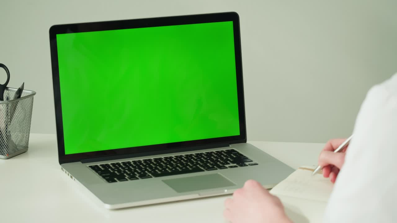 Person Working on Laptop and Taking Notes