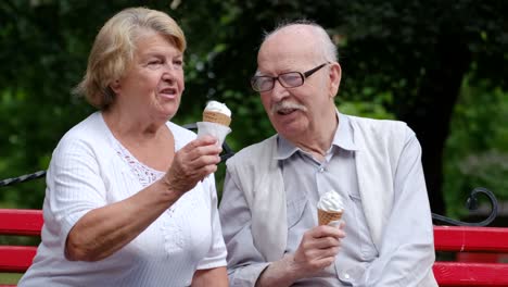 elderly couple enjoying ice cream on a bench in a park