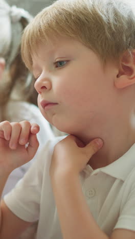 toddler boy and schoolgirl watch online lesson on laptop sitting at desk. attentive brother and sister study together at home closeup on blurred background