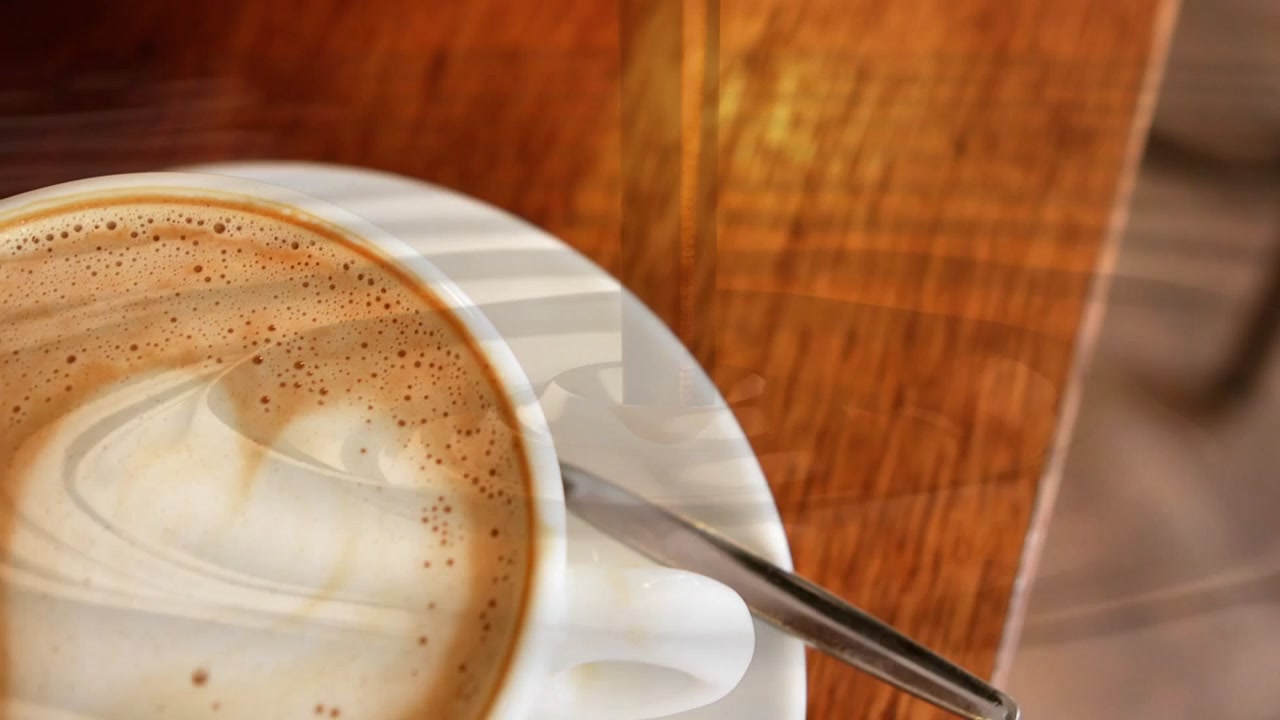 Il punto di vista si sposta verso la tazza, la telecamera rivela la latte art e il piattino mentre i riflessi di luce si muovono.