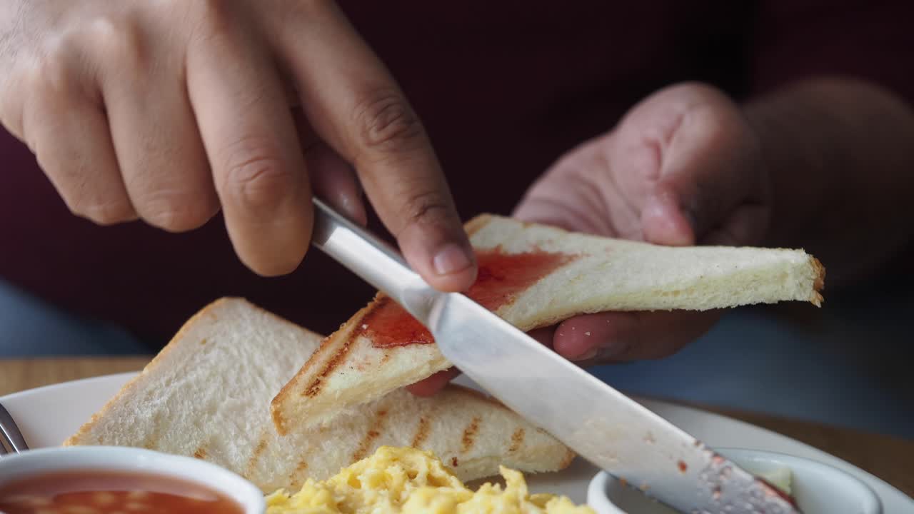 persona comiendo tostadas con mermelada y huevos para el desayuno
